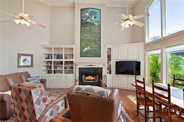 245 Youmans Rd, Midway, GA 31320 - living room with ceiling fan, ornamental molding, wood finished floors, a warm lit fireplace, and a towering ceiling
