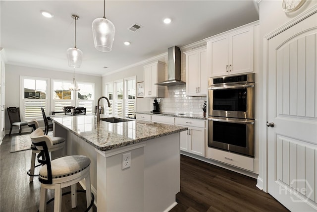 131 Como Dr, Pooler, GA 31322 - kitchen featuring double oven, wall chimney range hood, ornamental molding, dark wood-style floors, and a kitchen bar
