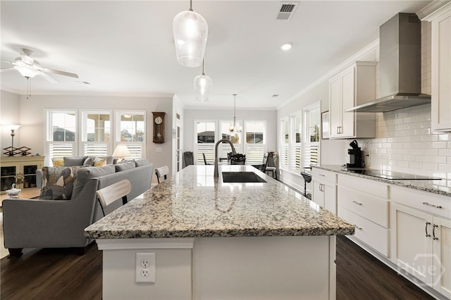 131 Como Dr, Pooler, GA 31322 - kitchen featuring wall chimney range hood, ornamental molding, dark wood-style floors, a kitchen island with sink, and black electric stovetop