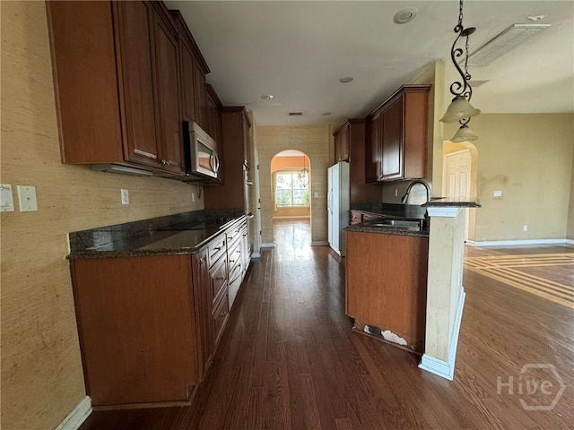 8 Fairgreen St, Savannah, GA 31407 - kitchen featuring stainless steel microwave, arched walkways, dark wood-style flooring, freestanding refrigerator, and decorative light fixtures
