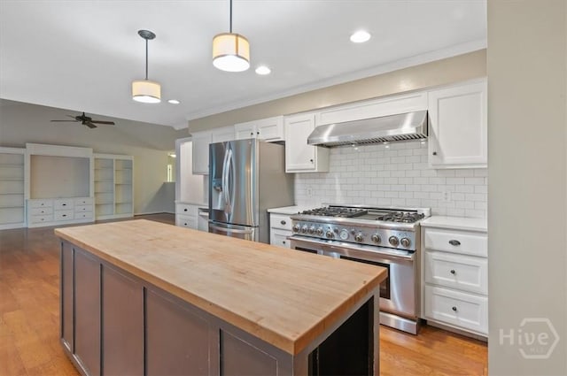 375 Hermitage Dr, Richmond Hill, GA 31324 - kitchen with wall chimney range hood, butcher block counters, stainless steel appliances, white cabinetry, and crown molding