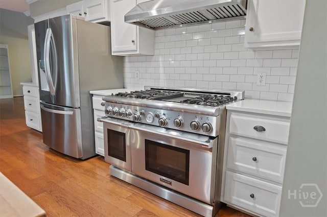 375 Hermitage Dr, Richmond Hill, GA 31324 - kitchen featuring stainless steel appliances, wall chimney exhaust hood, light countertops, white cabinets, and backsplash