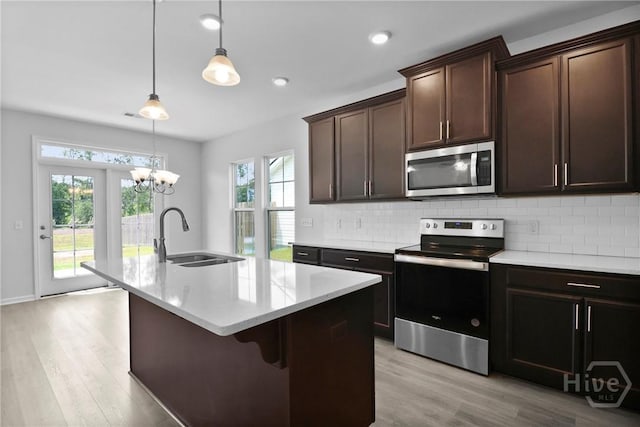 106 Brookline Dr, Savannah, GA 31407 - kitchen featuring appliances with stainless steel finishes, light wood-style floors, backsplash, a kitchen island with sink, and light countertops