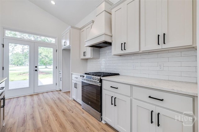 201 Dean Dr, Guyton, GA 31312 - kitchen with stainless steel gas stove, premium range hood, french doors, white cabinets, and light stone counters