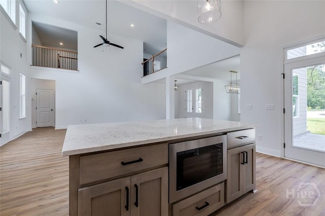 201 Dean Dr, Guyton, GA 31312 - kitchen featuring stainless steel microwave, a towering ceiling, plenty of natural light, light wood-style flooring, and ceiling fan