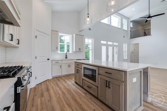 201 Dean Dr, Guyton, GA 31312 - kitchen with exhaust hood, stainless steel appliances, a high ceiling, light wood-style floors, and backsplash