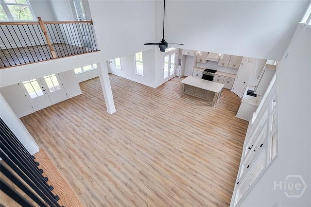 201 Dean Dr, Guyton, GA 31312 - unfurnished living room featuring a towering ceiling, light wood-style flooring, a ceiling fan, and french doors