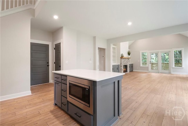 178 Cubbedge Dr, Rincon, GA 31326 - kitchen with stainless steel microwave, light wood-type flooring, light countertops, gray cabinetry, and a fireplace