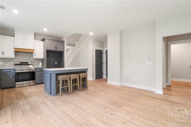 178 Cubbedge Dr, Rincon, GA 31326 - kitchen featuring stainless steel range with electric cooktop, light wood-type flooring, light countertops, tasteful backsplash, and a center island