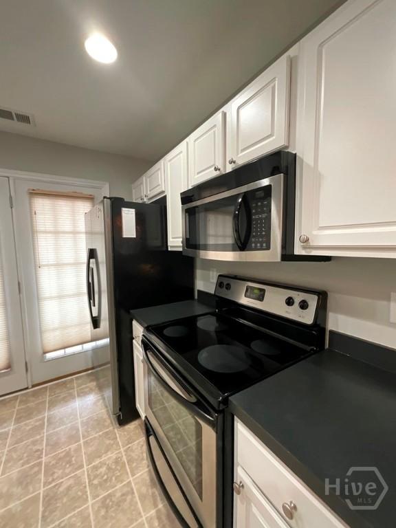 230 Opus Ct, Pooler, GA 31322 - kitchen featuring stainless steel appliances, dark countertops, white cabinets, and light tile patterned floors