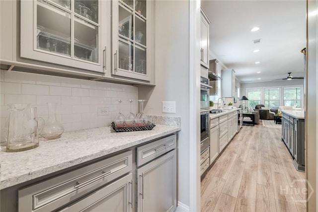 139 Harvest Hl, Pooler, GA 31322 - kitchen with open floor plan, light wood finished floors, backsplash, glass insert cabinets, and light stone counters