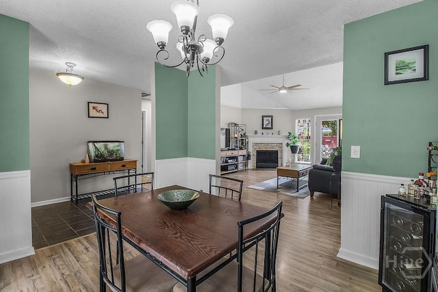 250 Laurel Hill Cir, Richmond Hill, GA 31324 - dining room with beverage cooler, wainscoting, ceiling fan, a textured ceiling, and a stone fireplace