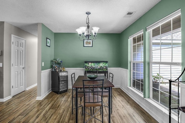 250 Laurel Hill Cir, Richmond Hill, GA 31324 - dining space featuring wood finished floors, a wainscoted wall, a textured ceiling, and a chandelier