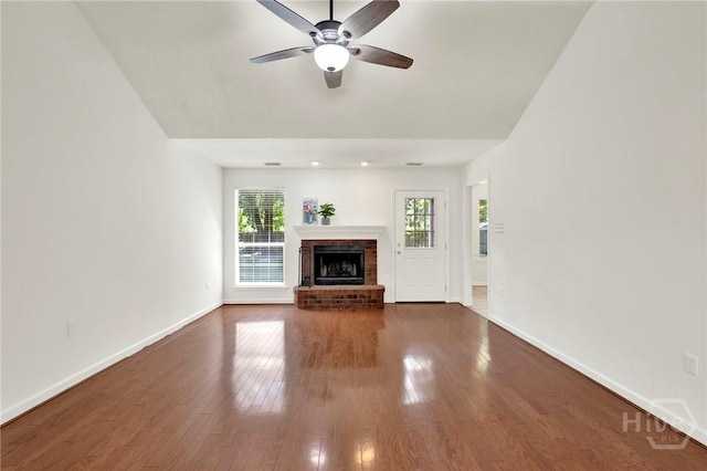 716 Greenwich Dr, Richmond Hill, GA 31324 - unfurnished living room with dark wood-style floors, ceiling fan, and a fireplace