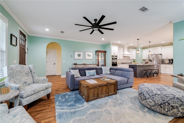 523 Goodman Dr, Midway, GA 31320 - living room featuring arched walkways, ceiling fan, light wood-style floors, recessed lighting, and ornamental molding