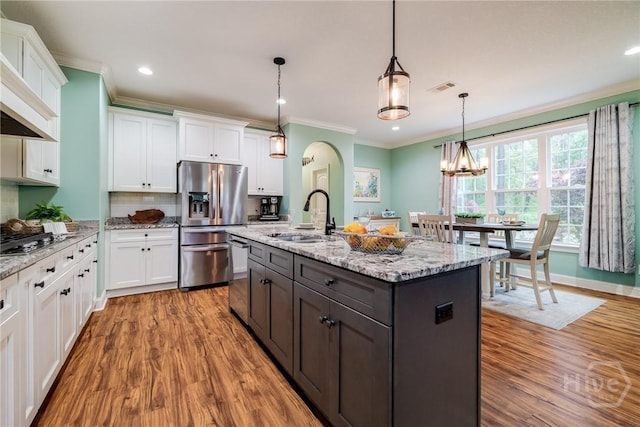 523 Goodman Dr, Midway, GA 31320 - kitchen with white cabinets, light wood finished floors, stainless steel appliances, ornamental molding, and light stone countertops