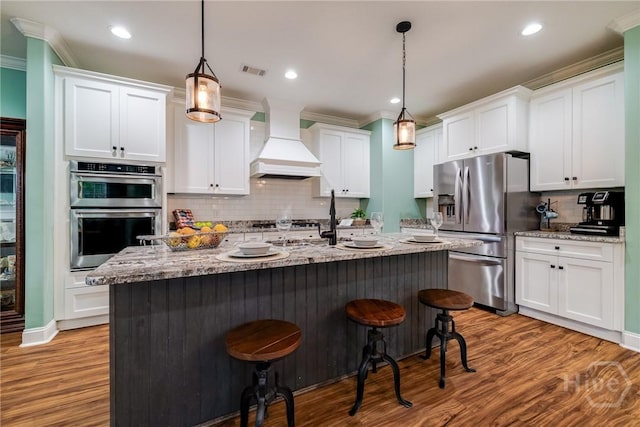 523 Goodman Dr, Midway, GA 31320 - kitchen featuring crown molding, appliances with stainless steel finishes, a kitchen bar, premium range hood, and decorative backsplash