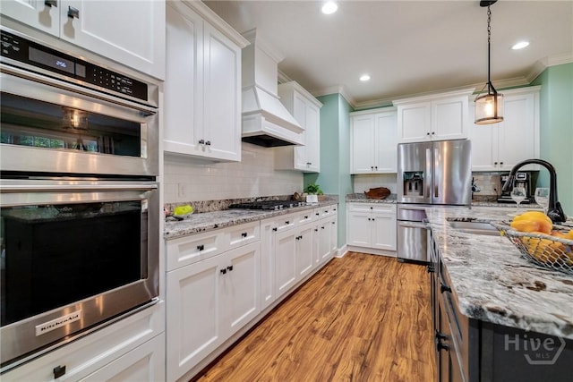 523 Goodman Dr, Midway, GA 31320 - kitchen featuring stainless steel appliances, ornamental molding, white cabinets, light wood finished floors, and pendant lighting