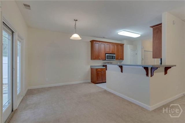 650 Summer Hill Way, Richmond Hill, GA 31324 - kitchen featuring a kitchen bar, brown cabinetry, light colored carpet, and stainless steel microwave