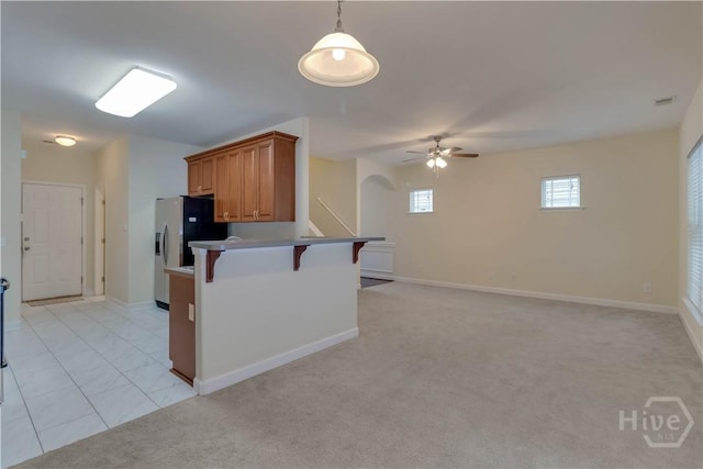 650 Summer Hill Way, Richmond Hill, GA 31324 - kitchen with a kitchen breakfast bar, arched walkways, ceiling fan, brown cabinets, and light carpet