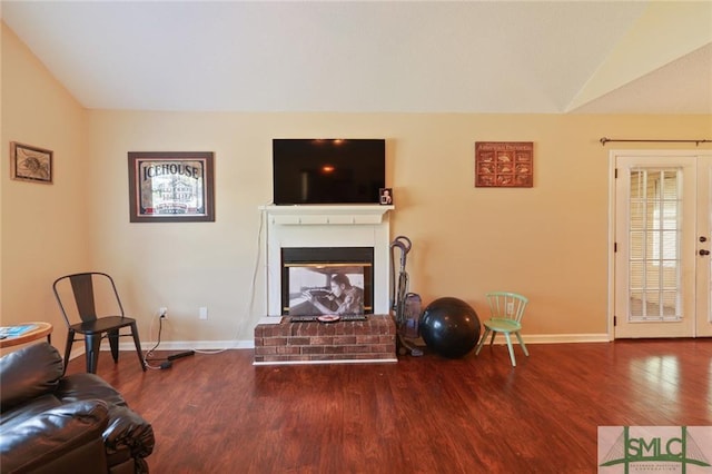 living room with vaulted ceiling, dark hardwood / wood-style flooring, and a fireplace