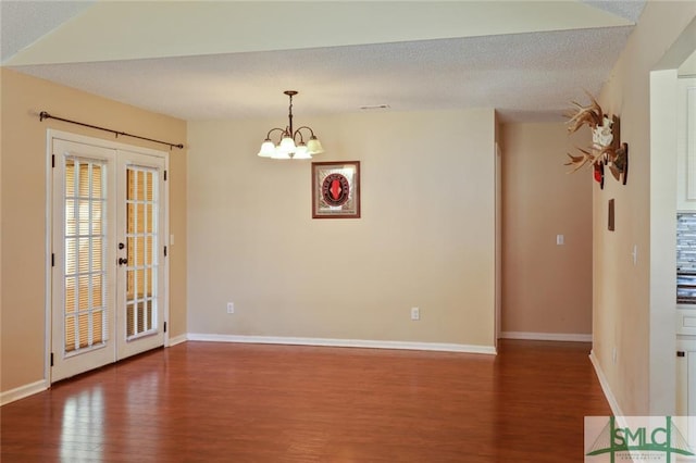 empty room featuring french doors, dark hardwood / wood-style flooring, a textured ceiling, and a chandelier