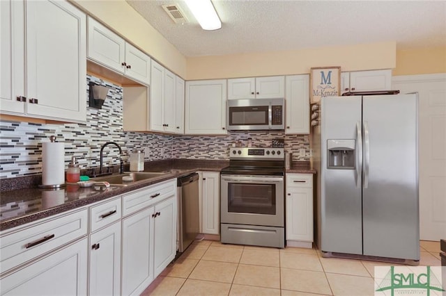 kitchen with appliances with stainless steel finishes, sink, backsplash, and white cabinetry