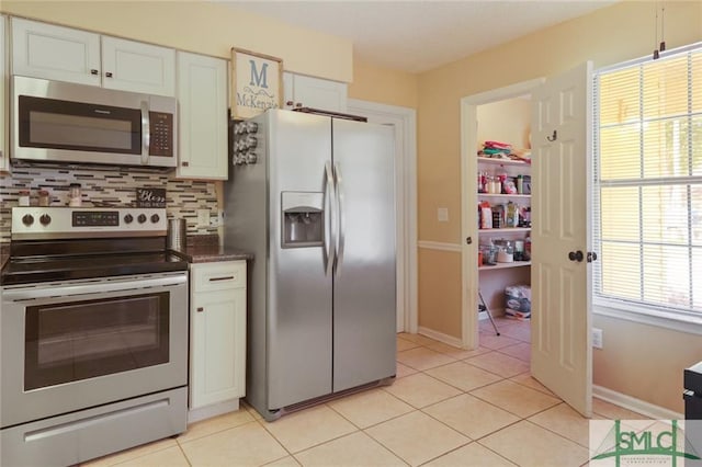 kitchen with backsplash, stainless steel appliances, light tile floors, and white cabinetry