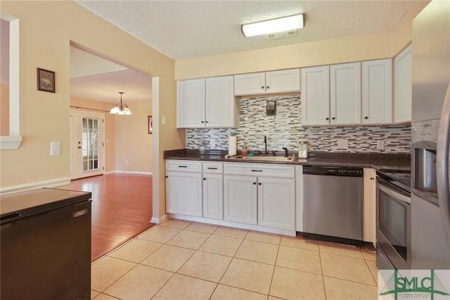 kitchen with stainless steel appliances, a notable chandelier, white cabinets, and light tile floors