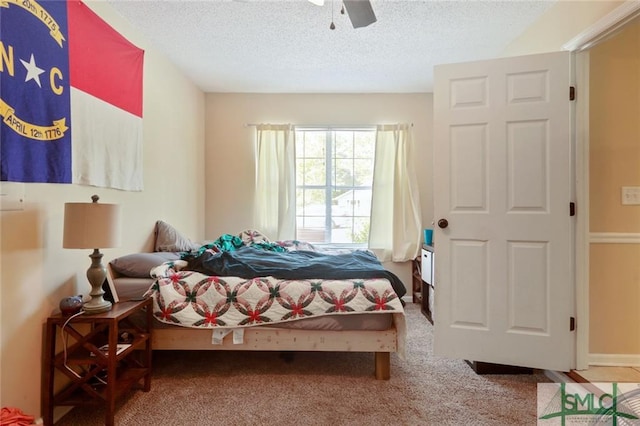 carpeted bedroom featuring ceiling fan and a textured ceiling