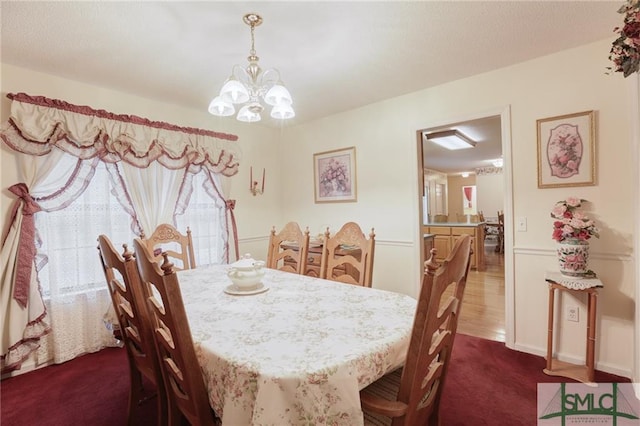 dining space with an inviting chandelier and dark carpet