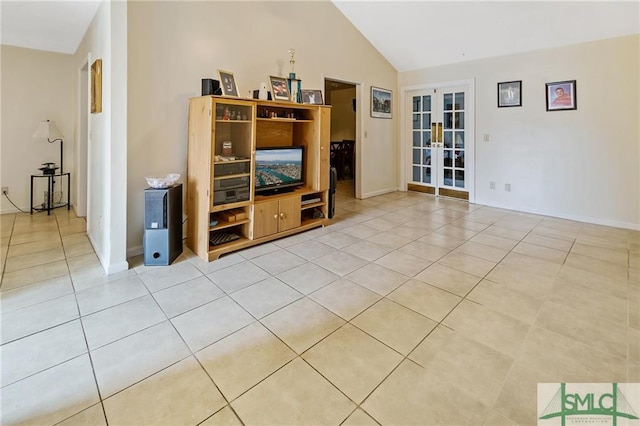 unfurnished living room with high vaulted ceiling, light tile floors, and french doors