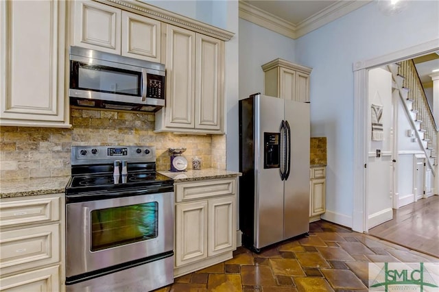 kitchen featuring backsplash, light stone countertops, cream cabinets, and appliances with stainless steel finishes