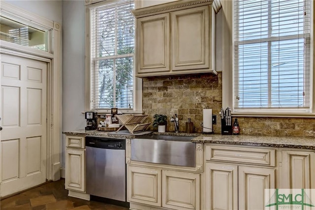 interior space featuring tasteful backsplash, cream cabinets, dishwasher, sink, and light stone countertops