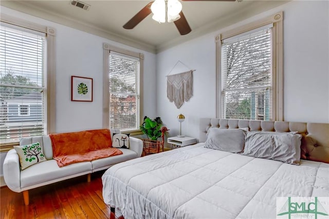 bedroom with ceiling fan, ornamental molding, multiple windows, and wood-type flooring