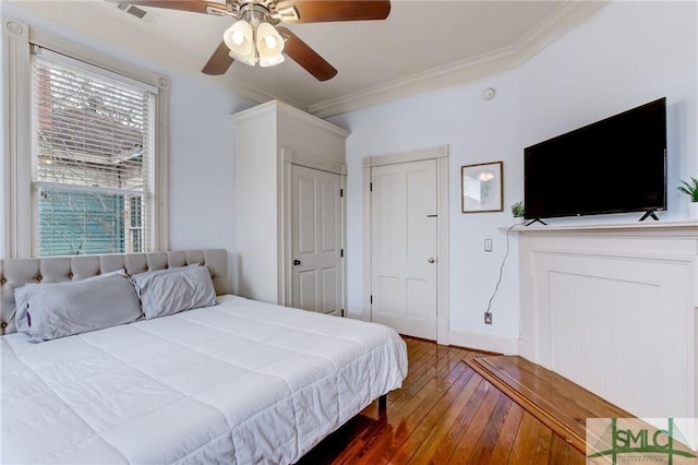 bedroom with crown molding, dark hardwood / wood-style floors, and ceiling fan