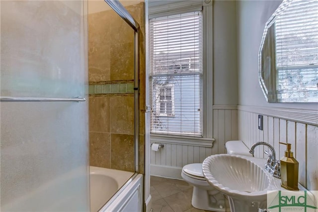 full bathroom featuring toilet, bath / shower combo with glass door, sink, and tile flooring