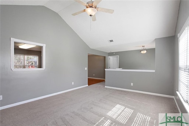 carpeted empty room with plenty of natural light, vaulted ceiling, and ceiling fan