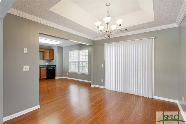 unfurnished room featuring a notable chandelier, crown molding, a tray ceiling, and wood-type flooring