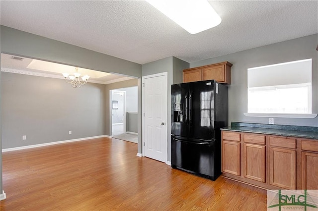 kitchen featuring a textured ceiling, a notable chandelier, light wood-type flooring, and black fridge