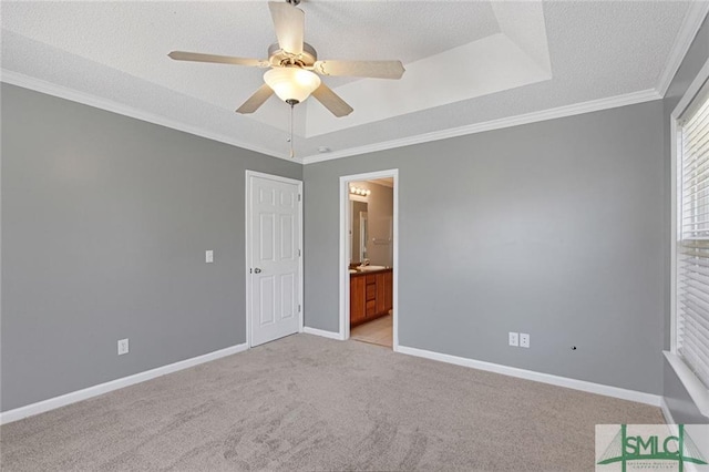 carpeted spare room with a tray ceiling, crown molding, and ceiling fan