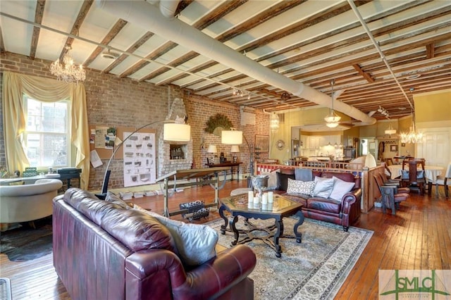 living room with brick wall, dark hardwood / wood-style flooring, and a chandelier