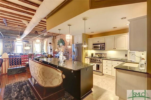 kitchen with appliances with stainless steel finishes, a kitchen island, a kitchen breakfast bar, sink, and white cabinets