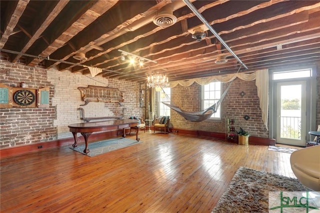 basement featuring brick wall, a wealth of natural light, and dark hardwood / wood-style flooring