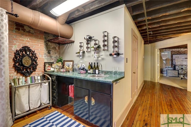 bar featuring wood-type flooring, sink, and beamed ceiling