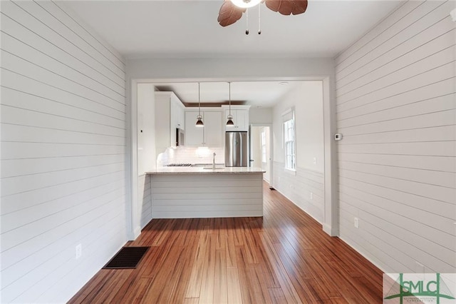 kitchen featuring hanging light fixtures, stainless steel fridge, ceiling fan, white cabinetry, and dark hardwood / wood-style floors