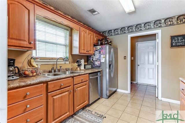 kitchen with stainless steel appliances, a textured ceiling, sink, and light tile floors