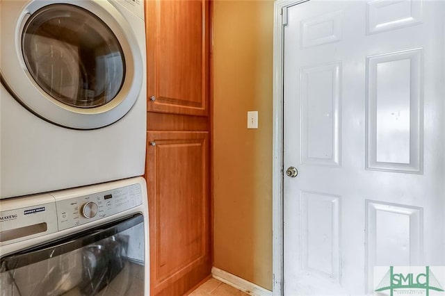 laundry area featuring light tile floors, cabinets, and stacked washer / drying machine