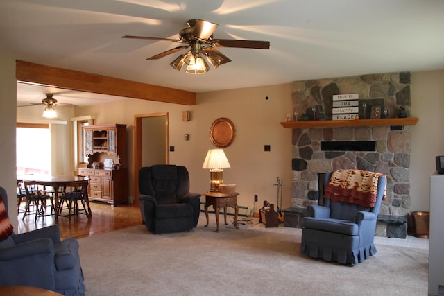 living room with light carpet, a baseboard radiator, ceiling fan, and a stone fireplace