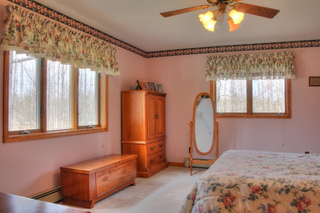 bedroom with ceiling fan, baseboard heating, and multiple windows